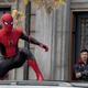 Spider-Man stands on top of a car while Doctor Strange looks on pensively in Spider Man No Way Home.